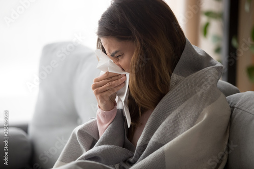 Принти на полотні Ill young woman covered with blanket blowing nose got flu