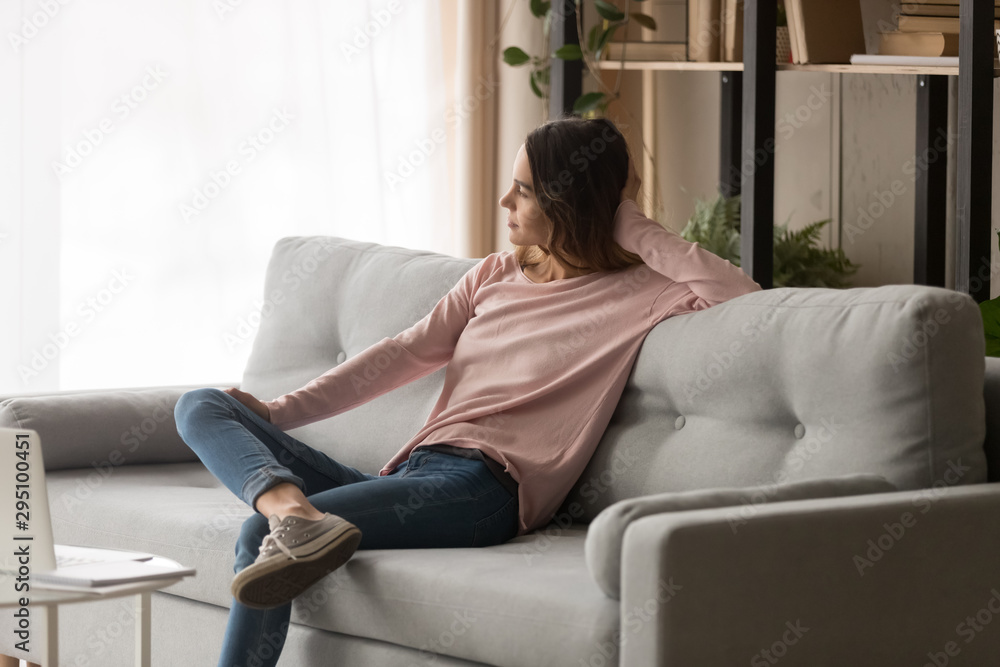 Relaxed dreamy girl sit on sofa enjoy peace of mind
