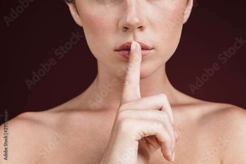Cropped image of shirtless young woman holding finger at her lips