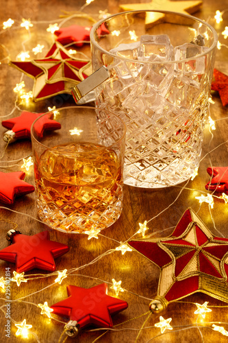 Crystal whisky ice bucket and a glass of whisky with christmas lights and red stars decorations