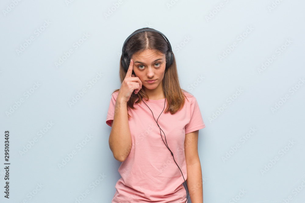 Young pretty caucasian woman thinking about an idea. She is listening to music with headphones. Young pretty caucasian woman thinking about an idea. She is listening to music with headphones.