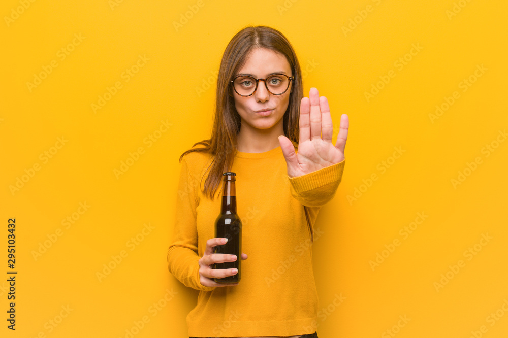 Young pretty caucasian woman putting hand in front. She is holding a beer. Young pretty caucasian woman putting hand in front. She is holding a beer.