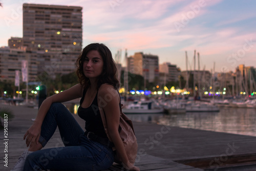 Young woman is sitting on a bench in a harbor © Cristian Blázquez