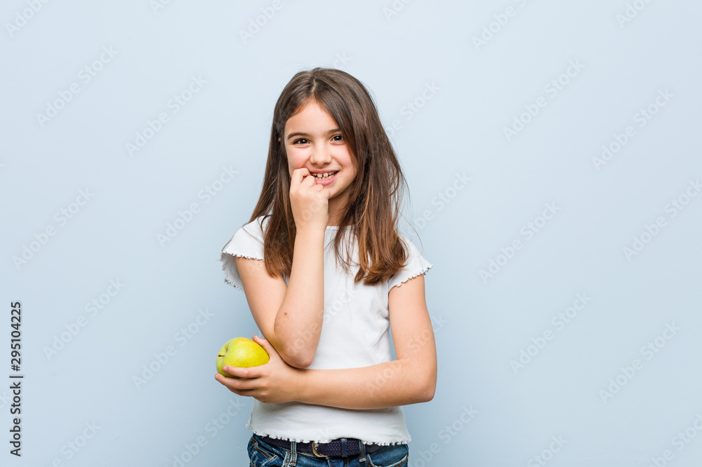 Little caucasian girl holding a green apple relaxed thinking about something looking at a copy space. Little caucasian girl holding a green apple relaxed thinking about something looking at a copy space.