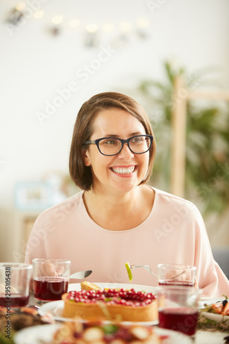 Happy young woman in eyeglasses sitting at the table and laughing while have dinner