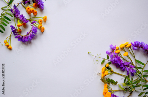 Fototapeta Naklejka Na Ścianę i Meble -  Festive beautiful composition of purple and yellow flowers and green leaves on a white background. Flat lay. Top view. Copy space.