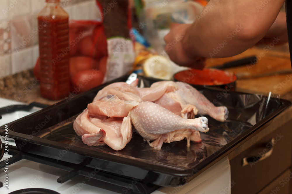 Cook prepares chicken for baking with spices in oven