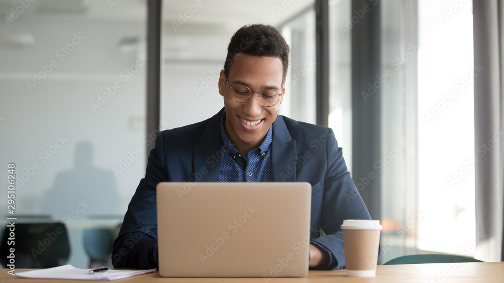 Happy african businessman working using laptop sit at office desk Happy african businessman working using laptop sit at office desk