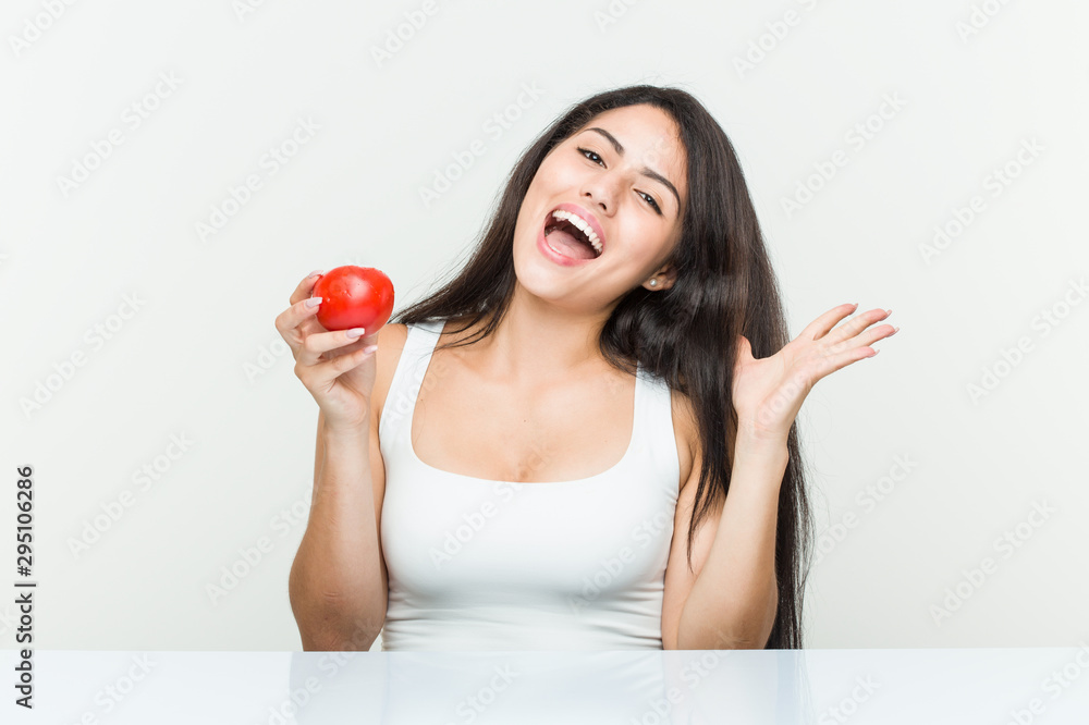 Young hispanic woman holding a tomato celebrating a victory or success Young hispanic woman holding a tomato celebrating a victory or success
