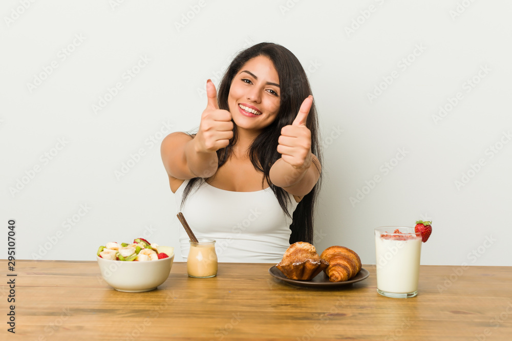 Young curvy woman taking a breakfast with thumbs ups, cheers about something, support and respect concept. Young curvy woman taking a breakfast with thumbs ups, cheers about something, support and respect concept.