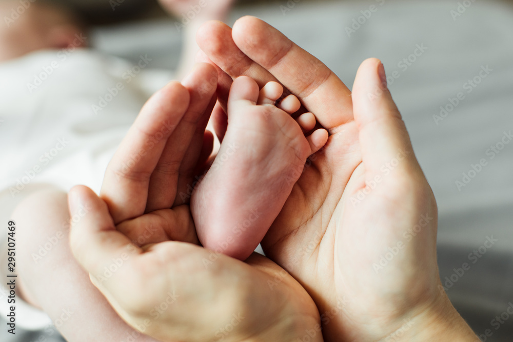 Mother holding newborn baby feet in hands. Mom taking care about infant child after taking bath. Parents childcare. Children healthcare and happy family Mother holding newborn baby feet in hands. Mom taking care about infant child after taking bath. Parents childcare. Children healthcare and happy family