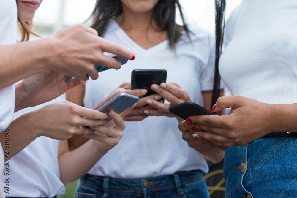 Fototapeta premium Cropped shot of young women using modern phones. Closeup shot of female hands typing on smartphones. Technology concept