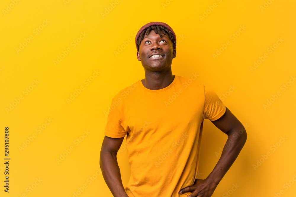 Young black man wearing rastas over yellow background confused, feels doubtful and unsure.