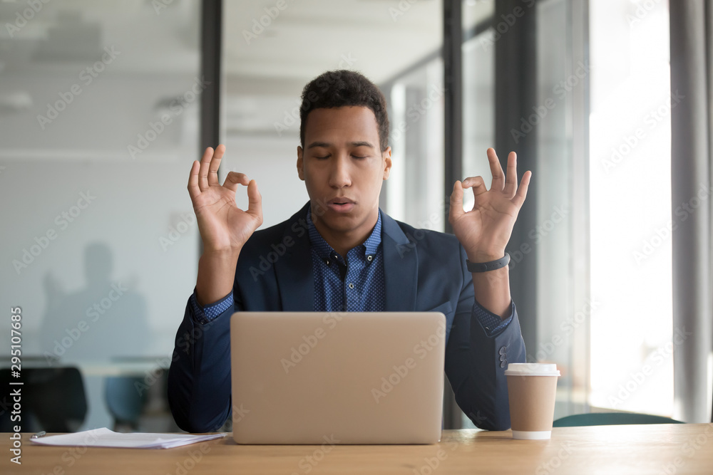 Calm mindful black businessman in suit meditate at work desk Calm mindful black businessman in suit meditate at work desk