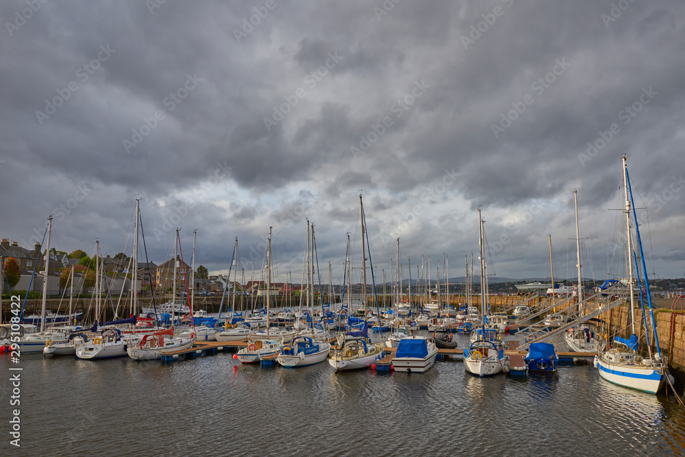The small town of Tayport overlooking its harbour where the Yachts and Motor Boats are moored in the new Marina, with Threatening afternoon clouds coming in.