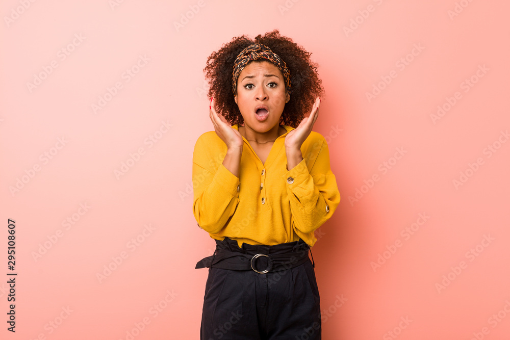 Young african american woman against a pink background surprised and shocked. Young african american woman against a pink background surprised and shocked.