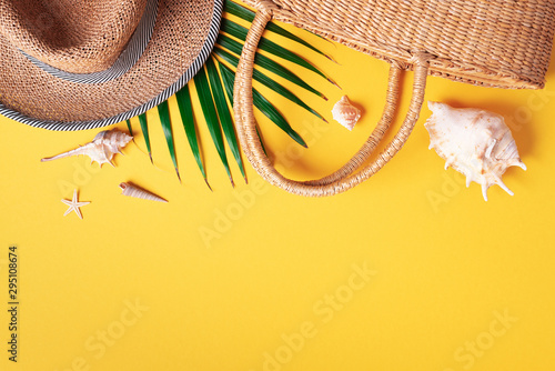 Summer fashion flat lay. Stylish straw bag, hat, palm leaves, shells on trendy yellow background. Top view. Copy space. Sustainable lifestyle. Zero waste, plastic free concept. photo