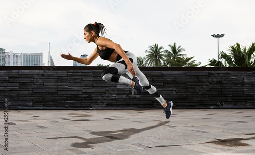 Sporty young woman running on sidewalk