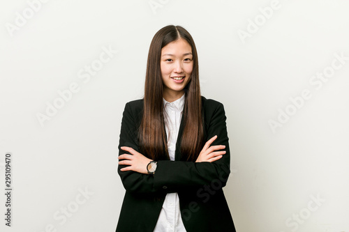 Young pretty chinese business woman who feels confident, crossing arms with determination.