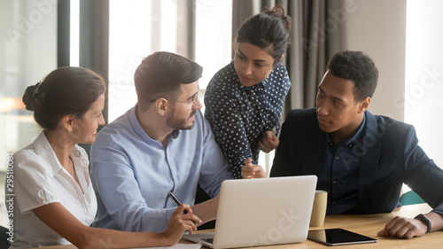 Business team of four brainstorm gathered in office with laptop