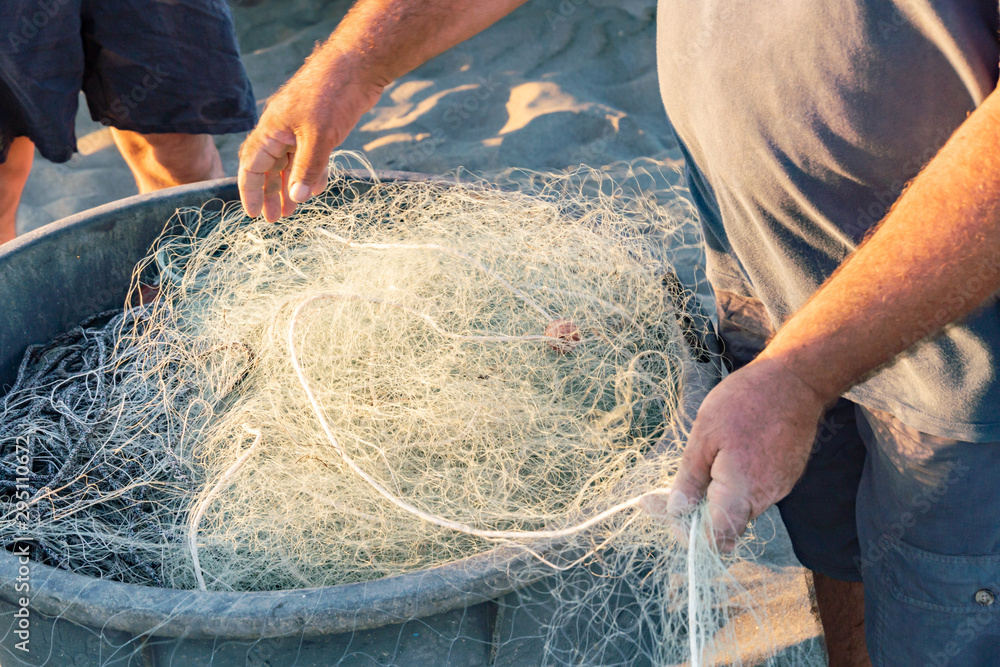 Untangling the net. Fishermen pulling and mending the traditional