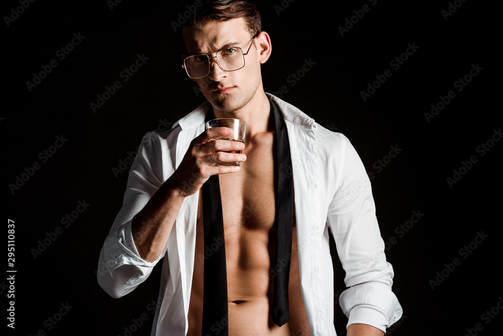 sexy man in glasses and suit holding glass with whiskey isolated on black sexy man in glasses and suit holding glass with whiskey isolated on black