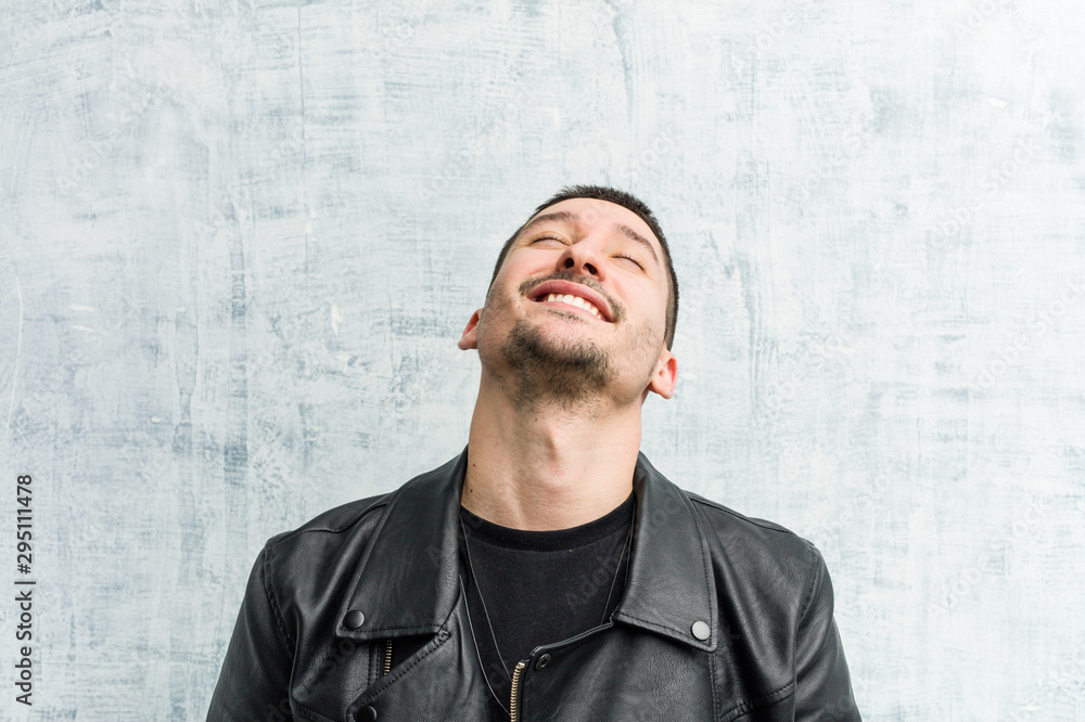 Young rocker man relaxed and happy laughing, neck stretched showing teeth. Young rocker man relaxed and happy laughing, neck stretched showing teeth.