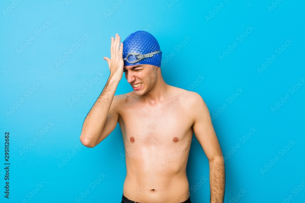 Young swimmer man forgetting something, slapping forehead with palm and closing eyes.