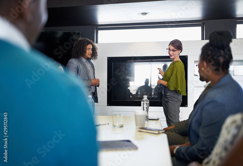 Multi-ethnic group of coworkers discussing in modern meeting room with female boss and laptop computer