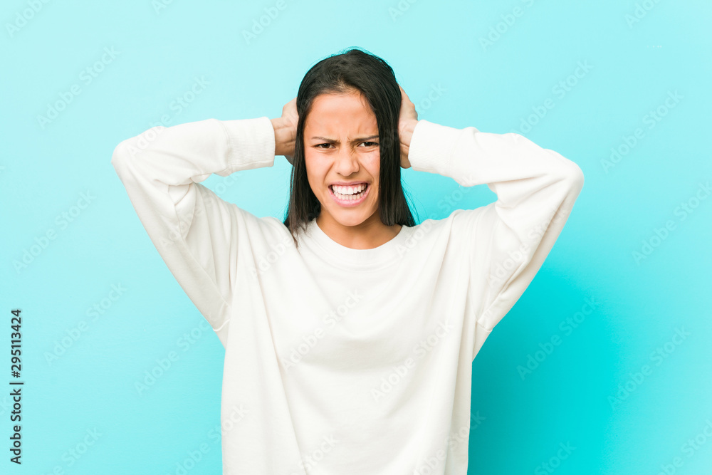 Young pretty hispanic woman covering ears with hands trying not to hear too loud sound. Young pretty hispanic woman covering ears with hands trying not to hear too loud sound.