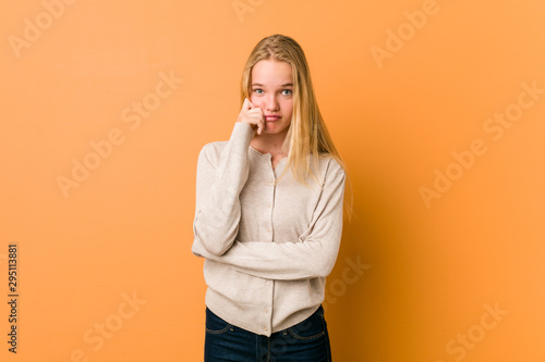 Cute caucasian teenager posing standing against a orange background