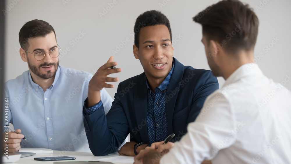 Three diverse business men talking sit at negotiation table Three diverse business men talking sit at negotiation table