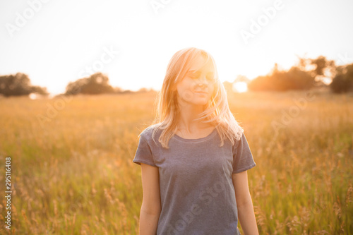 Young woman standing on the field at sunset. Eyes closed