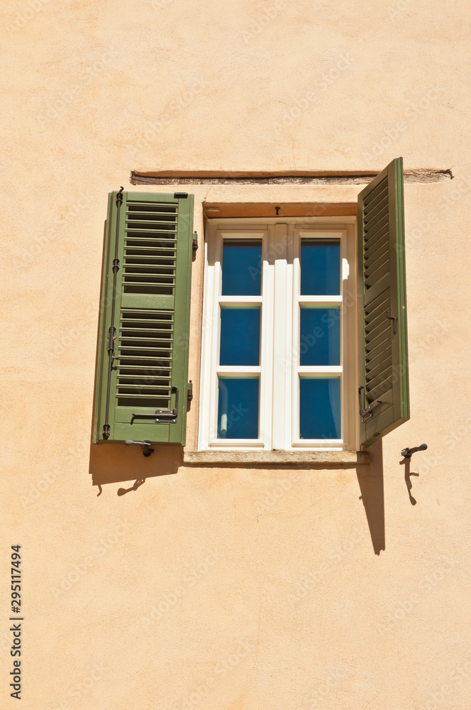 Front view, medium distance of a window with open green, antique shutters on a home in the village of Barbaresco, in the Piedmont wine region of Italy