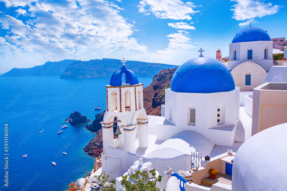 Naklejka premium Piękne miasto Oia na wyspie Santorini, Grecja. Tradycyjna biała architektura i greckie cerkwie z niebieskimi kopułami nad kalderą na Morzu Egejskim. Malownicze tło podróży.