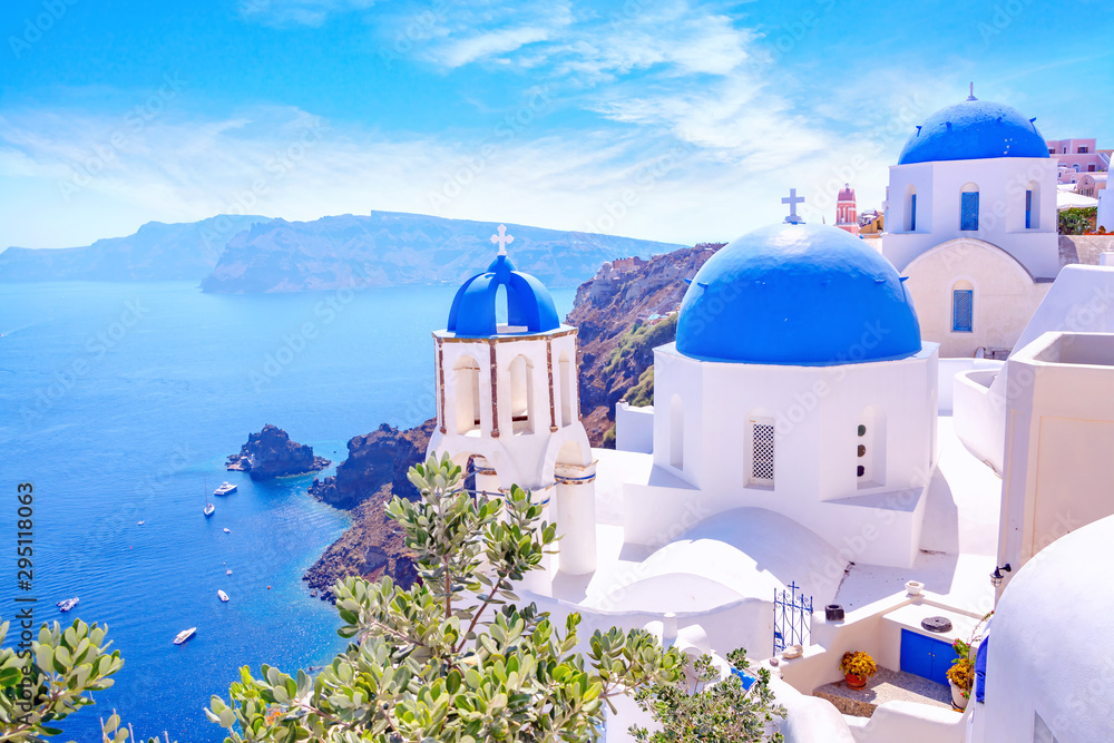 Beautiful Oia town on Santorini island, Greece. Traditional white architecture and greek orthodox churches with blue domes over the Caldera, Aegean sea. Scenic travel background.