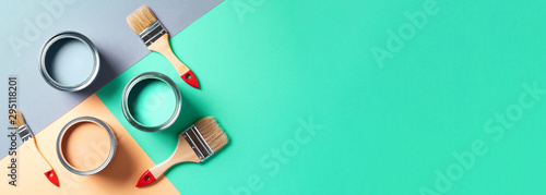 Metal paint cans and paint brushes on multicolor background. Top view. Copy space. Trendy green color concept photo