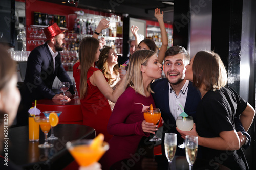 Two women kissing man at nightclub