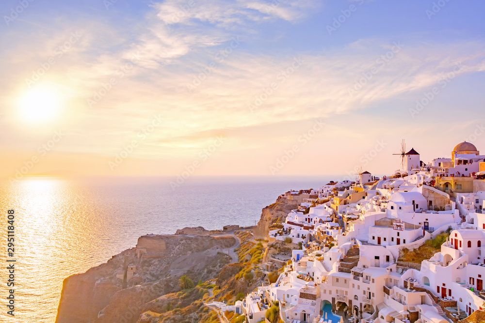 Beautiful view of picturesque village of Oia with traditional white architecture  and windmills in Santorini island in Aegean sea at sunset, Greece. Scenic travel background.