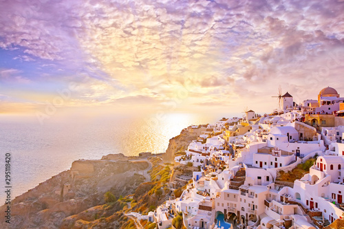 Beautiful view of picturesque village of Oia with traditional white architecture  and windmills in Santorini island in Aegean sea at sunset, Greece. Scenic travel background. © MarinadeArt