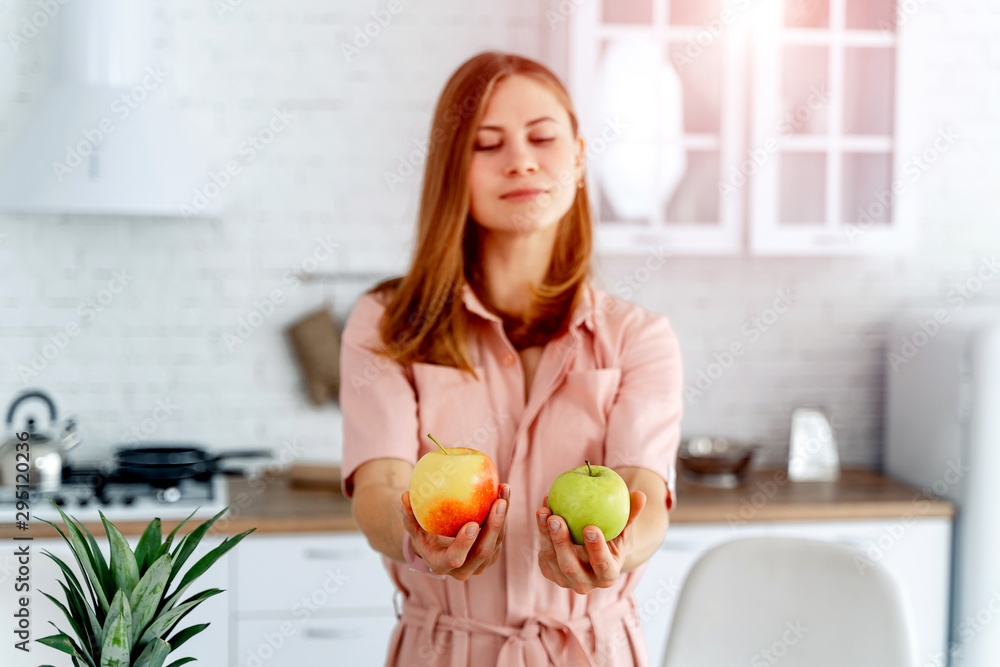 Woman in kitchen ready to prepare meal with vegetables and fruits. Woman is holding apples.Kitchen background. Healthy food. Vegans. Vegeterian.