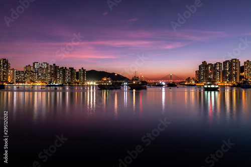 Sunset over the cable-stayed bridge with silhouette of car crossing the sea bay © Earnest Tse