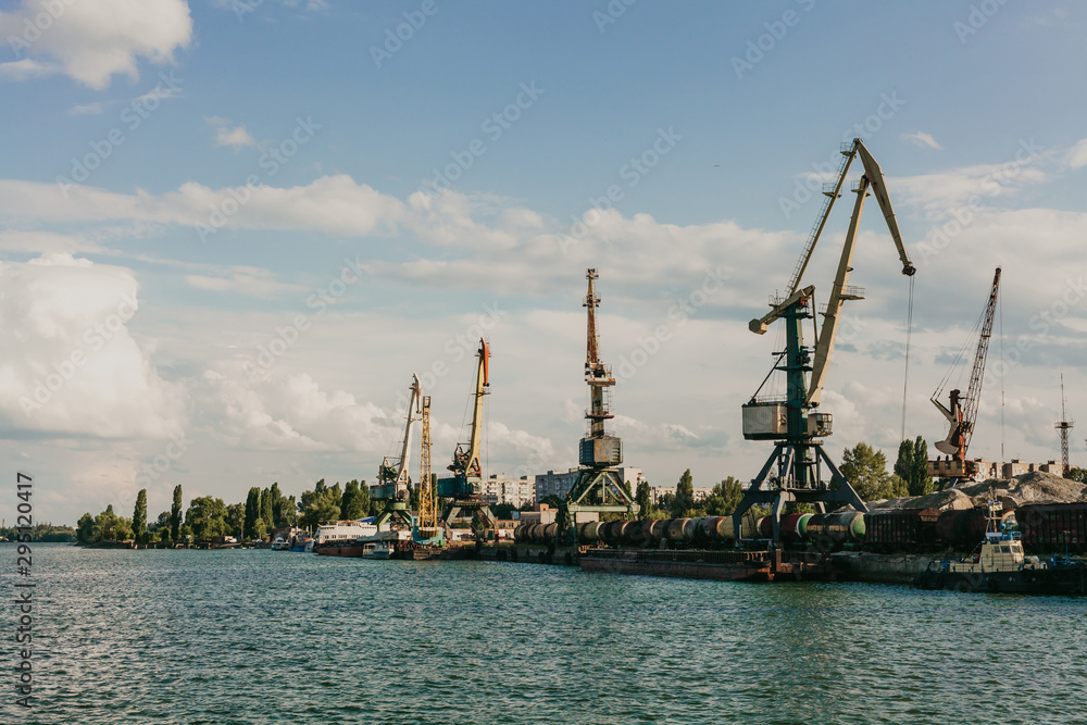 Portal cranes in river port on sky background