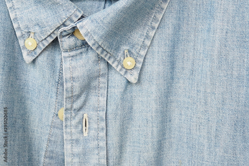 Closeup of light blue jeans shirt with buttons and collar for fashion, sewing, lifestyle and quality textile concept Closeup of light blue jeans shirt with buttons and collar for fashion, sewing, lifestyle and quality textile concept