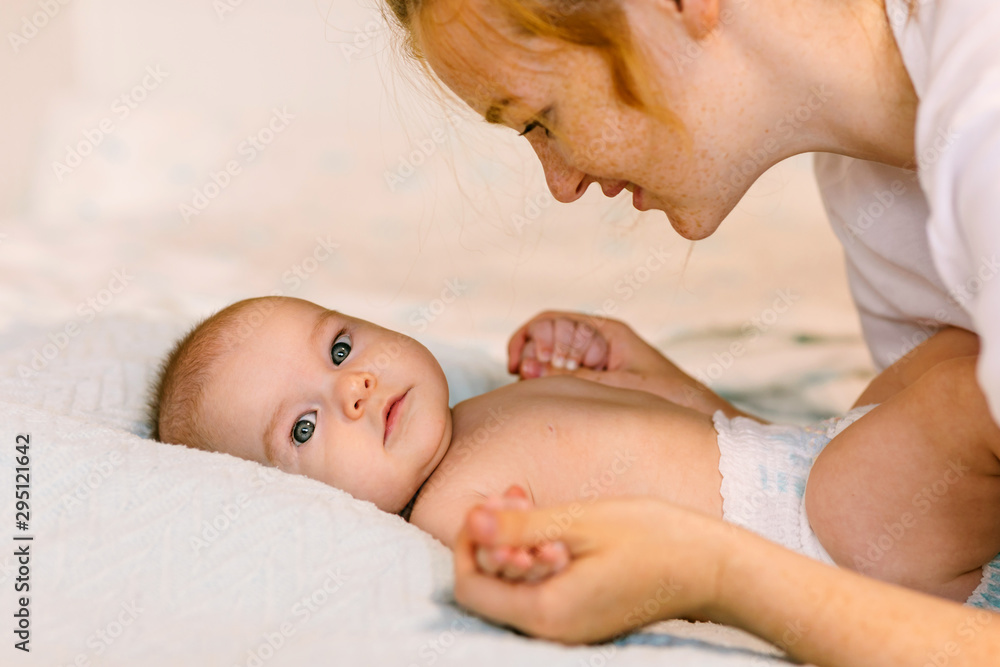 Mom hugs with her newborn baby in bed. Four month old baby. Baby care, tenderness, motherhood Mom hugs with her newborn baby in bed. Four month old baby. Baby care, tenderness, motherhood