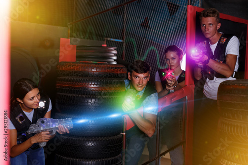 Group of positive friends playing laser tag game with laser g