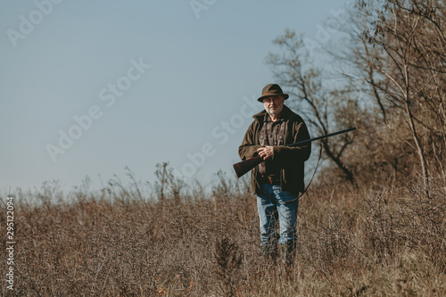 Hunter with gun against blue sky