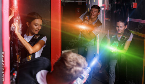 Group of young people playing laser tag game with laser guns