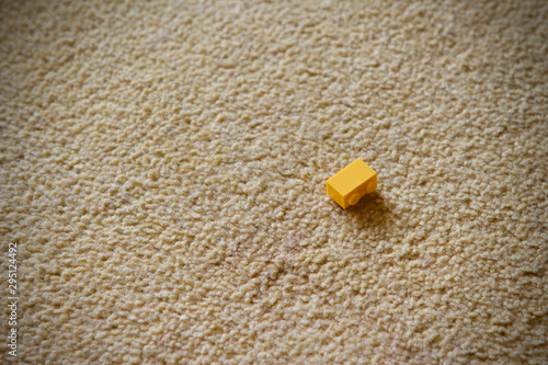 Childs yellow plastic building block on a carpet