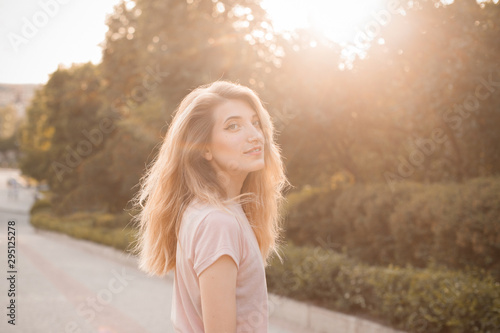 Young woman with long hair walking down the street under sunlight